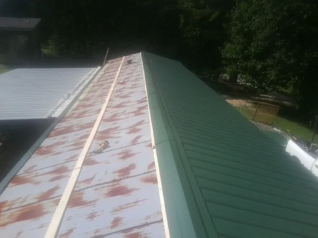 Old rusted panels beside newly installed green metal roofing — Wind Damage Roof Repair by Roofing Brothers in Fort Cobb