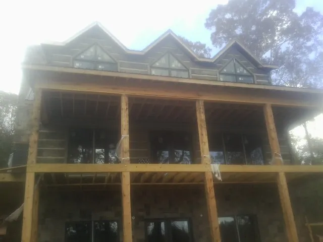 Dormers and porch framing on a large log home under construction — Roof Coating work by our crew in Fort Cobb