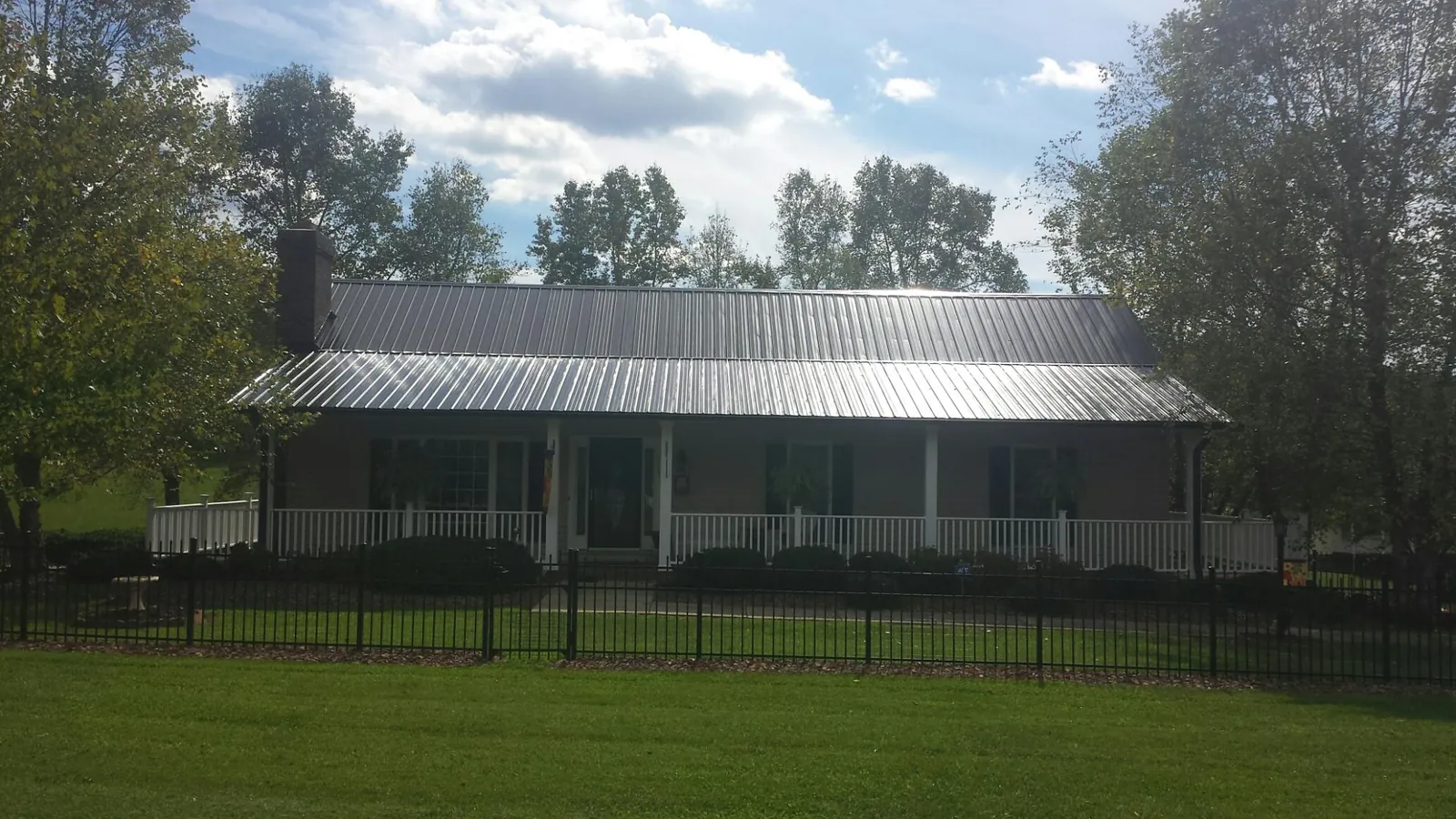 Gray metal roof on a brick ranch with a full width front porch — Gutter Guard Installation work by our crew in Fort Cobb