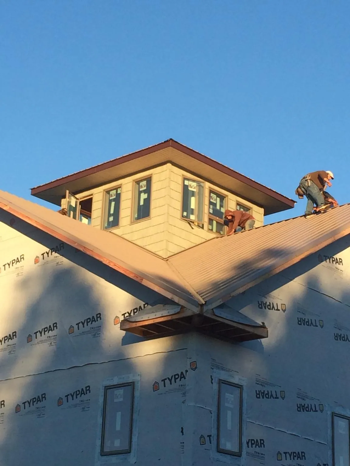 Roofers working around a rooftop cupola on a new metal roof at sunset — Roof Waterproofing in Fort Cobb by Roofing Brothers